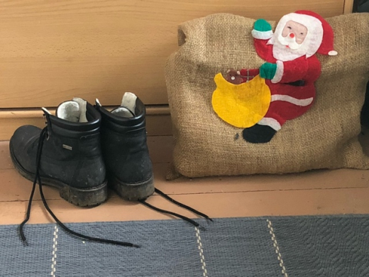 Ein paar Stiefel neben einem Jutesack mit aufgeklebtem WEihnachstsmann.