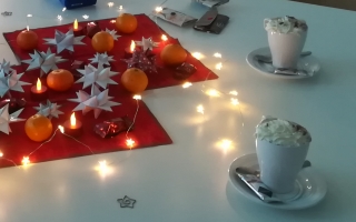 Tisch mit Lichterkette, Fröbelsternen und Basteleien - Tassen mit heißer Schokolade mit Sahne