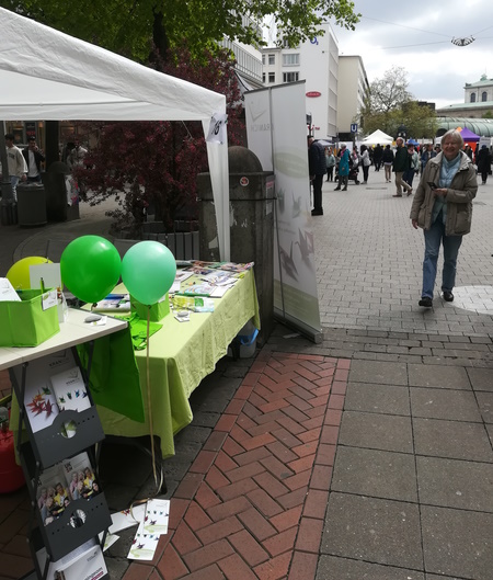 Foto von unserem Stand am Selbsthilfetag in Hannover dieses Jahr. Ein Frau geht auf unseren Stand zu.